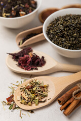 Various types of tea in wooden spoons on a light texture background. Tea mixture. Range. Black, green, herbal and hibiscus teas. Top view. Copy space.Various types of tea in wooden spoons on a light t