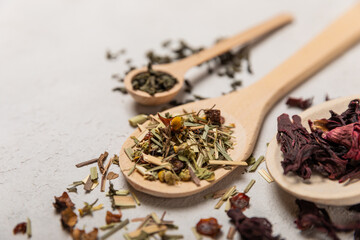 Various types of tea in wooden spoons on a light texture background. Tea mixture. Range. Black,...