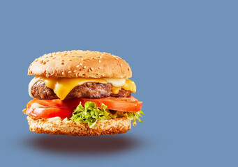 juicy cheeseburger on a blue background. fast food concept, cheeseburger banner

