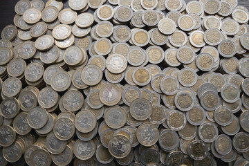 Pile of Colombian coins of 500 and 1000 denominations over wooden background. Ideal for economy, money, banks, save money and finance.
