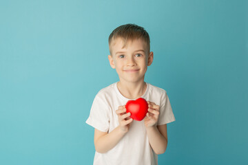 Children holding the red heart on a blue background. Concept of love, care, faith, hope, purity. Place for text. Flat fly