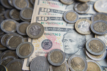 Bills of ten dollars between a pile of colombian coins of 500 and 1000
