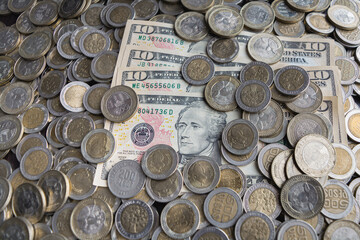 Bills of ten dollars between a pile of colombian coins of 500 and 1000
