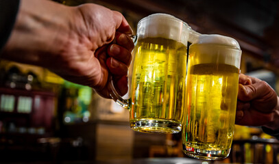 two glass of beer in hand. Beer glasses clinking in bar or pub