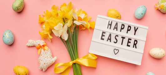 Text Happy Easter, light yellow spring bouquet and easter decor on pink background
