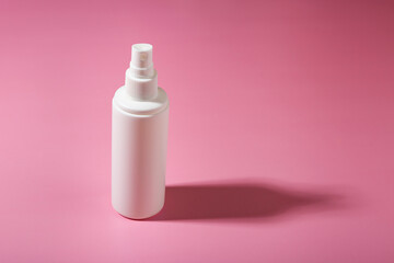 Cosmetic container with cosmetic product on a pink background.