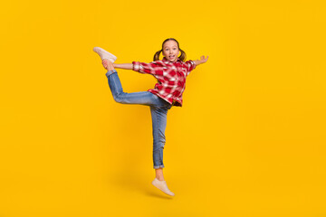 Photo of pretty adorable schoolkid dressed plaid shirt jumping high practicing gymnastic isolated yellow color background