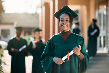 Happy African American graduate student with university diploma looking at camera.