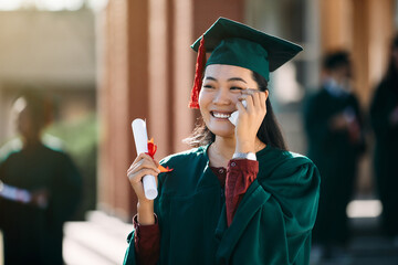 Happy Asian female student feeling emotional after receiving diploma on her graduation day.