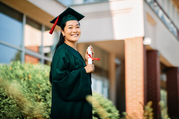 Happy Asian college student on her graduation day looking at camera.
