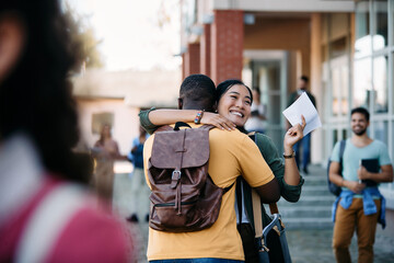 Happy Asian student hugs her African American boyfriend after passing an exam at the university.