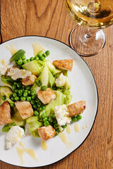 fresh appetizing salad of chicken green peas, feta cheese and cucumber on a wooden table in a restaurant