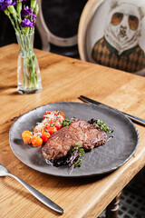 two steaks on a dark plate with sauce and cherry tomatoes on a dark background. banner for advertising meat and steak restaurant