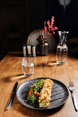 bruschetta with shrimp and salad on a dark plate on a wooden table in a beautiful interior, vertical photo