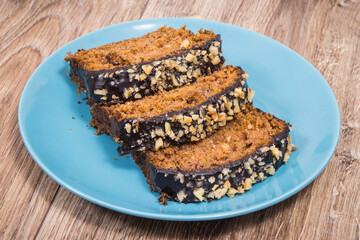 Homemade pastry made of zucchini with nuts and raisin on blue plate. Wooden background