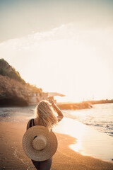 young woman in a swimsuit with a beautiful figure on the seashore at sunset. Selective focus