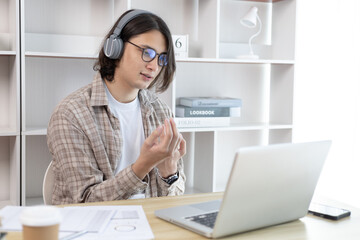 Young Asian men are greeting friends and teachers through video chats and greeting them with cheerful expressions, Online communication , Stay home, New normal, VDO Call, Internet learning.