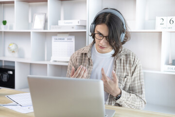 Young Asian men are greeting friends and teachers through video chats and greeting them with cheerful expressions, Online communication , Stay home, New normal, VDO Call, Internet learning.