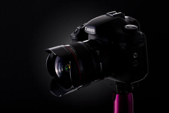 Old and used camera Canon EOS 7D with a EF-14mm f/2.8L USM prime lens in a studio shot over black background