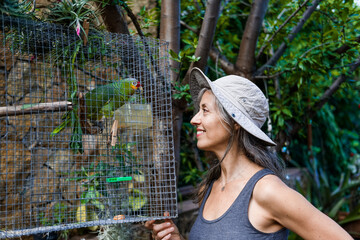 woman with parrot smiling at home - obrazy, fototapety, plakaty