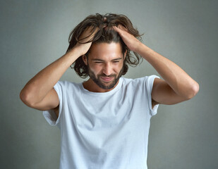 This is so frustrating. Studio shot of a young man looking upset against a grey background.