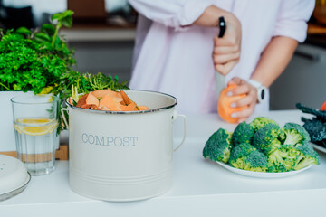 Compost the kitchen waste, recycling at home. Compost bin with vegetables cutted leftovers on the...