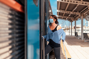 A young woman in protective mask getting on the train