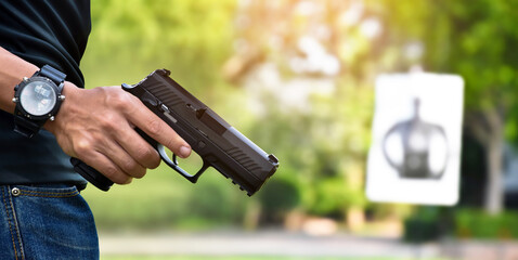 Automatic black 9mm pistol gun holding in hands of shooter and ready to aim to the man-target...