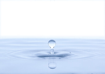 Splash and a ball of water on a blue background. Reflection on the surface of the water.