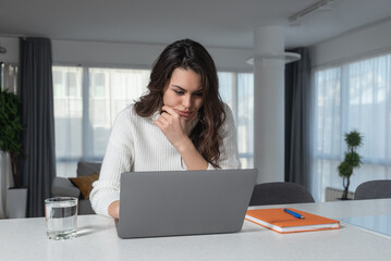 Young woman freelance software and web developer programmer working on laptop from home. Female business person developing new computer and mobile phone app for customers paying online and booking.