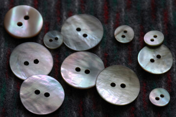 Fototapeta premium Buttons made of natural mother of pearl against the background of coarse fabric.