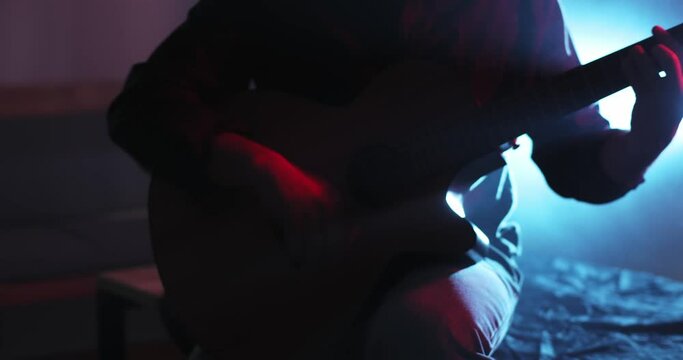 fast dynamic playing of a man on a classical guitar in the backlight of blue and red in smoke. playing flamenco on the guitar. middle plan