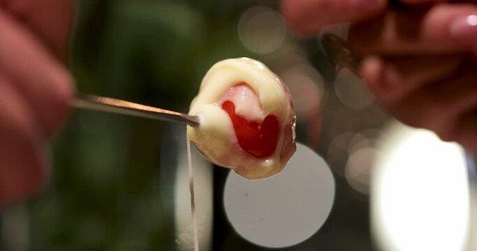 the hands of a man and a woman are dipping cherry tomatoes into the processed fundu cheese at a table in a restaurant. romantic dinner by candlelight. macro