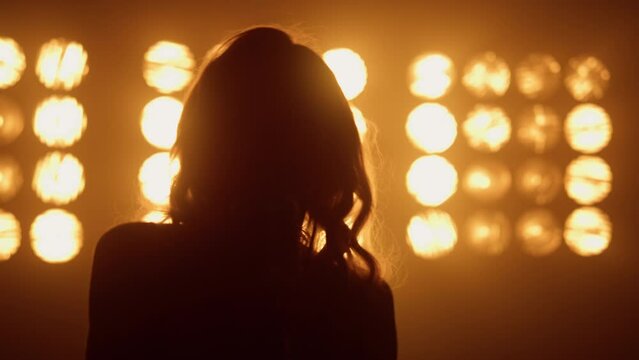 Silhouette professional woman vocalist performing in night club lights close up.