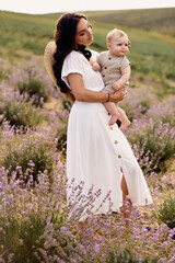 attractive young mother playing with her baby in a lavender field