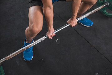 An anonymous man doing sumo deadlifts. Using an alternate grip to pick up the barbell. Overhand on left hand and underhand on the right.