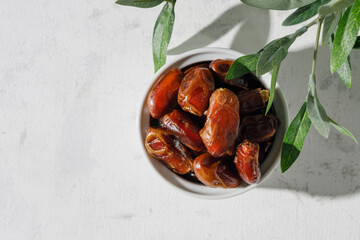 Dried dates in a white cup on a white background. A sunny day.