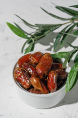 Dried dates in a white cup on a white background. A sunny day.