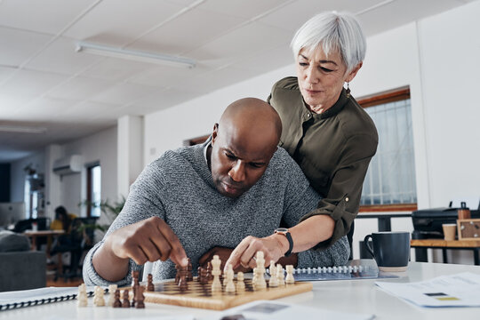 Nothing Can Disrupt His Focus. Shot Of A Mature Businessman Getting Help From A Colleague While Playing Chess In His Office.