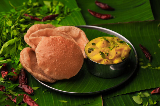 south indian famous breakfast poori or puri with potato curry served in a plate with banana leaf clo