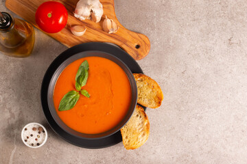 Fresh, healthy tomato soup with basil, pepper, garlic, tomatoes and bread on wooden background. Spanish gazpacho soup. Lentils and pumpkin soup.