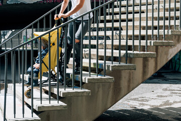 Mom drags a stroller with a child up the stairs