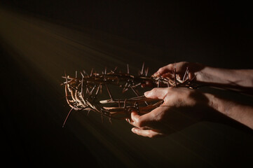 Crown of thorns in hands and sun rays