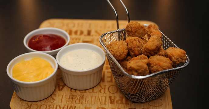 Closeup shot of delicious crispy fried breaded chicken patties served with different souces