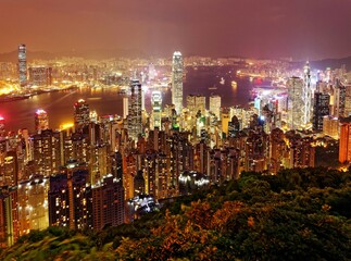 Naklejka premium Night scenery of Hong Kong viewed from top of Victoria Peak with city skyline of crowded skyscrapers along Victoria Harbour and Kowloon area across seaport ~ Beautiful cityscape of Hongkong at sunset