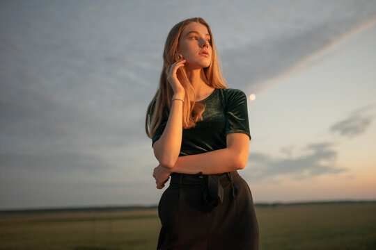 Young woman watching the sunset on a wasteland