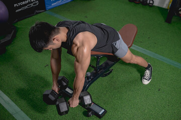 A fit asian guy does chest supported dumbbell row on an incline bench. Hanging the weights down...