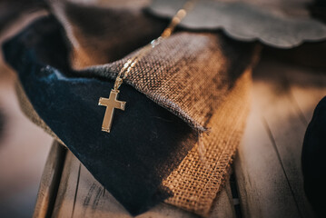 Golden cross with chain on a piece of fabric on a wooden table