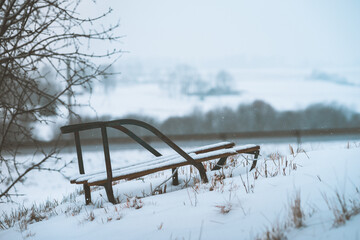 Closeup shot of metal sled covered with snow on snowy ground during daytime with blurred background