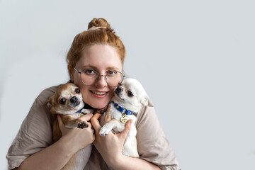 Woman hug two small dogs and looking to the camera. Isolated on grey background. Concept of Pet Love